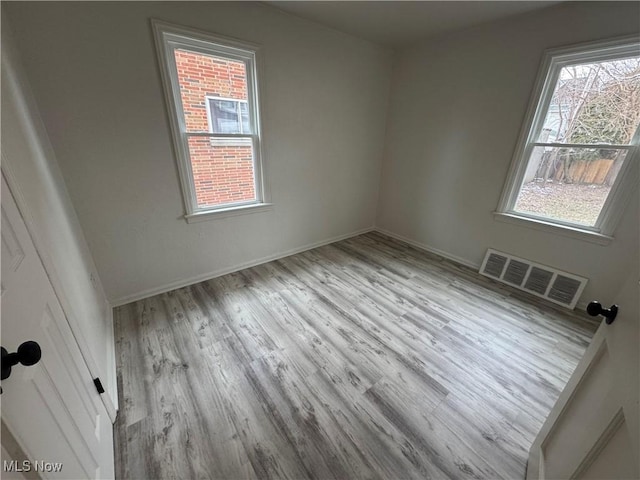 empty room with baseboards, visible vents, and wood finished floors