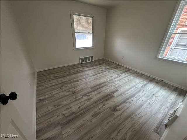 empty room featuring visible vents, baseboards, and wood finished floors