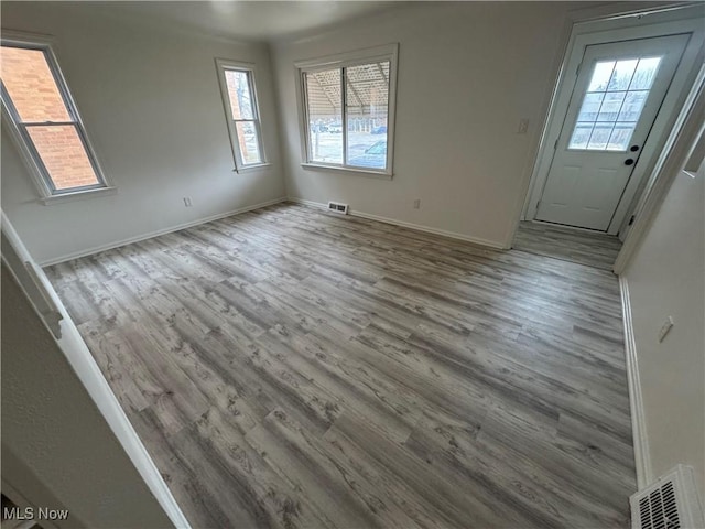 interior space with baseboards, visible vents, and wood finished floors