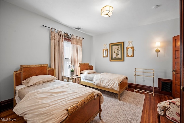 bedroom featuring wood finished floors, visible vents, and baseboards