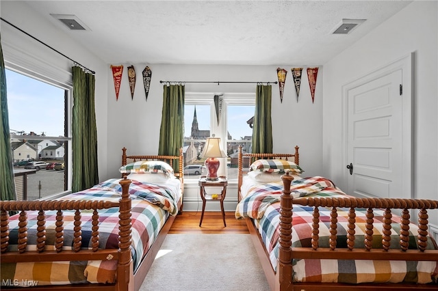 bedroom with a textured ceiling, multiple windows, and visible vents