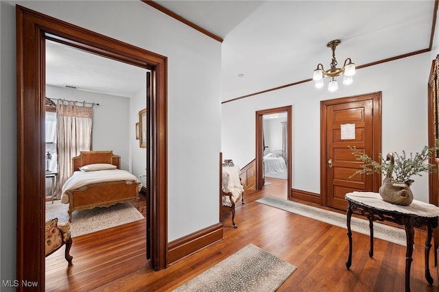 entrance foyer with baseboards, a notable chandelier, ornamental molding, and wood finished floors