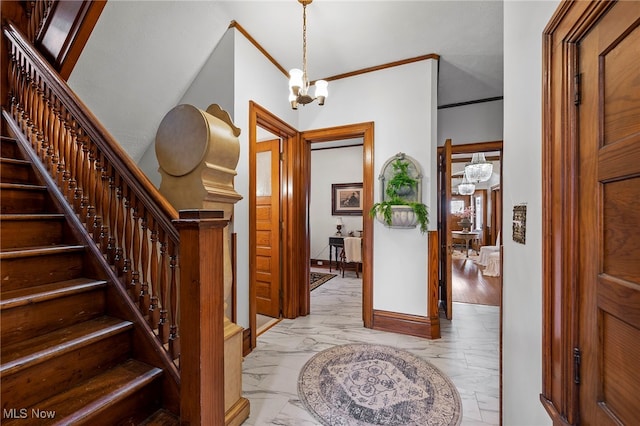 foyer entrance featuring marble finish floor, crown molding, a notable chandelier, stairway, and baseboards