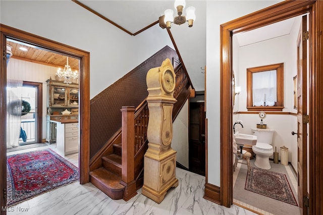 interior space with marble finish floor, ornamental molding, wainscoting, and an inviting chandelier