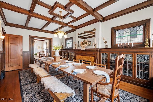 dining room with coffered ceiling, dark wood finished floors, a wainscoted wall, beamed ceiling, and a chandelier