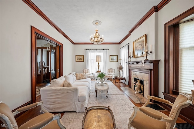 living room featuring a notable chandelier, a fireplace, baseboards, light wood-type flooring, and crown molding