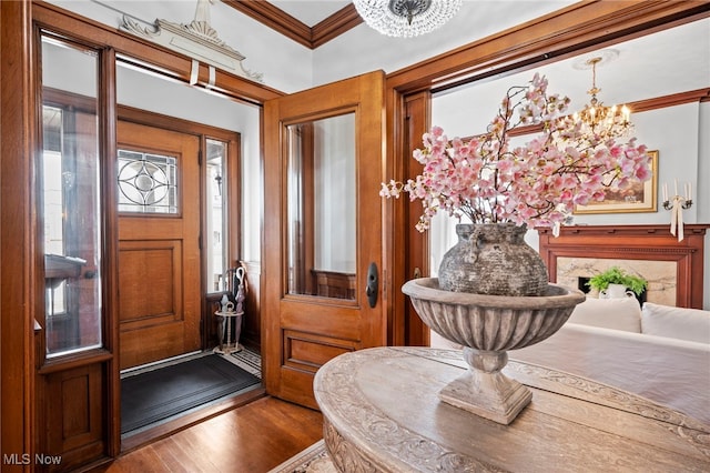 entrance foyer featuring a chandelier, crown molding, and wood finished floors