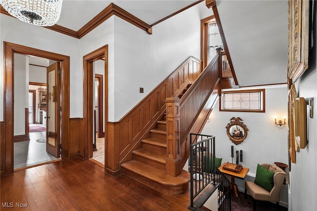 stairway with a wainscoted wall, wood-type flooring, and ornamental molding