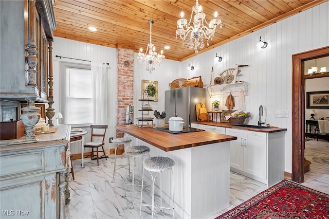 kitchen with marble finish floor, wooden counters, a sink, and freestanding refrigerator