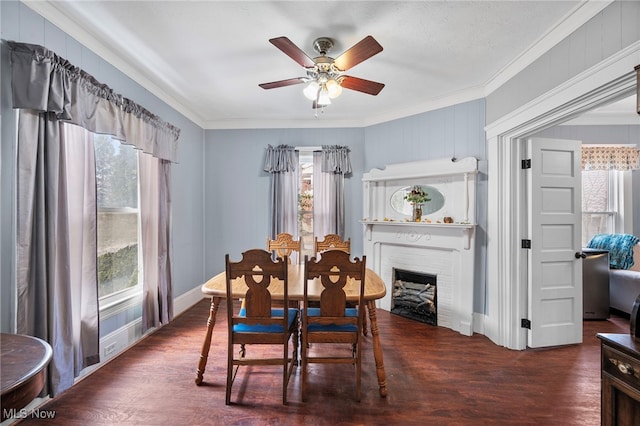 dining room with a wealth of natural light, a brick fireplace, ornamental molding, and wood finished floors