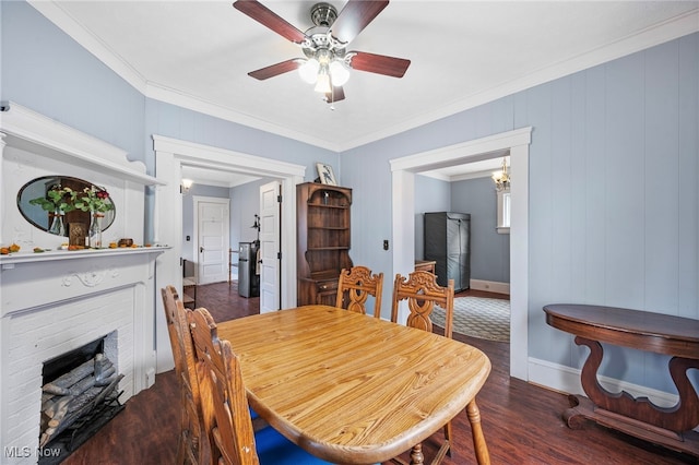 dining space featuring a fireplace, wood finished floors, a ceiling fan, baseboards, and ornamental molding