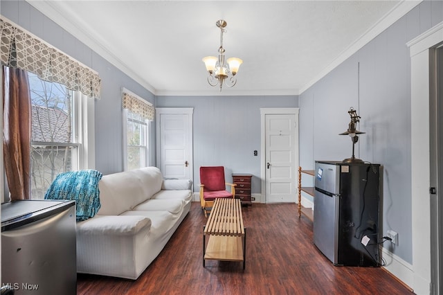 living area with ornamental molding, dark wood-type flooring, a notable chandelier, and baseboards