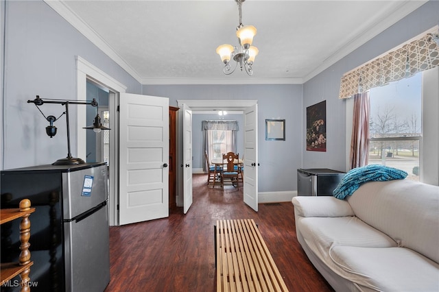 living room featuring dark wood-type flooring, crown molding, baseboards, and an inviting chandelier