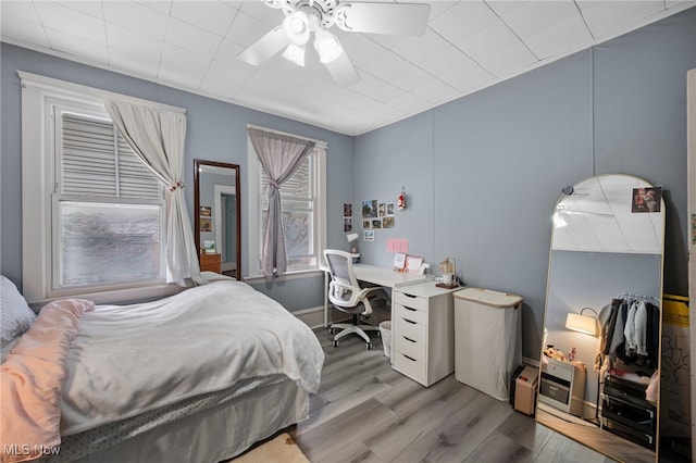 bedroom featuring wood finished floors, a ceiling fan, and baseboards