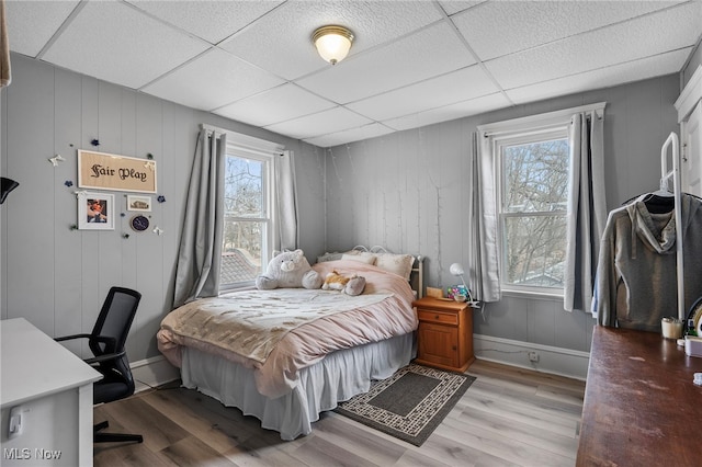 bedroom featuring light wood-style floors, a drop ceiling, and baseboards