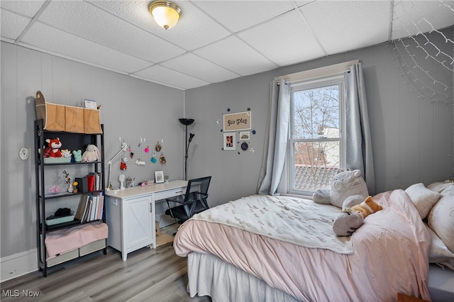 bedroom with light wood-style floors and a drop ceiling