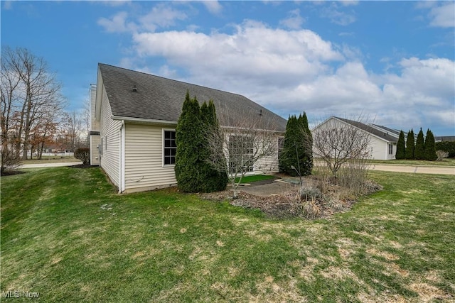 view of side of home featuring a lawn and roof with shingles