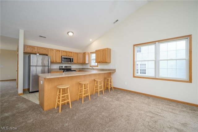 kitchen with appliances with stainless steel finishes, visible vents, a peninsula, and light carpet