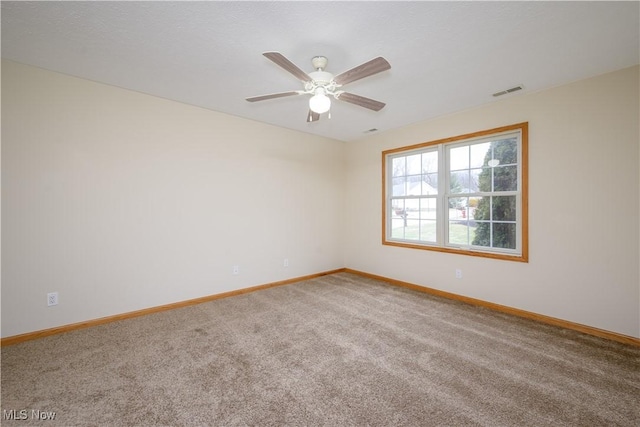 empty room with carpet floors, visible vents, baseboards, and a ceiling fan