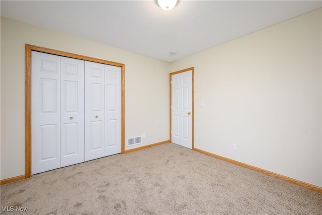 unfurnished bedroom featuring baseboards, a closet, visible vents, and carpet flooring