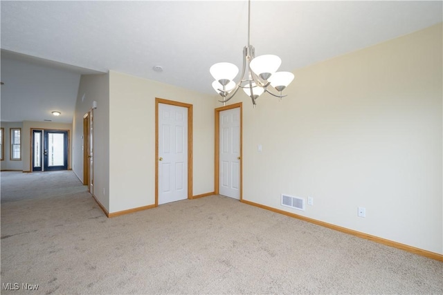 empty room with carpet flooring, a notable chandelier, visible vents, and baseboards