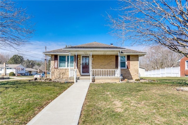 bungalow with covered porch, brick siding, a front yard, and fence