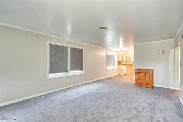 carpeted spare room featuring baseboards, visible vents, and crown molding