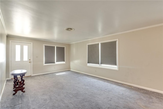 spare room with carpet floors, baseboards, visible vents, and crown molding