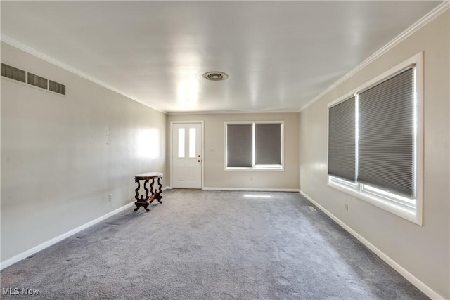 carpeted spare room featuring visible vents, crown molding, and baseboards