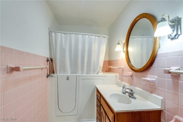 bathroom featuring wainscoting, tile walls, and vanity