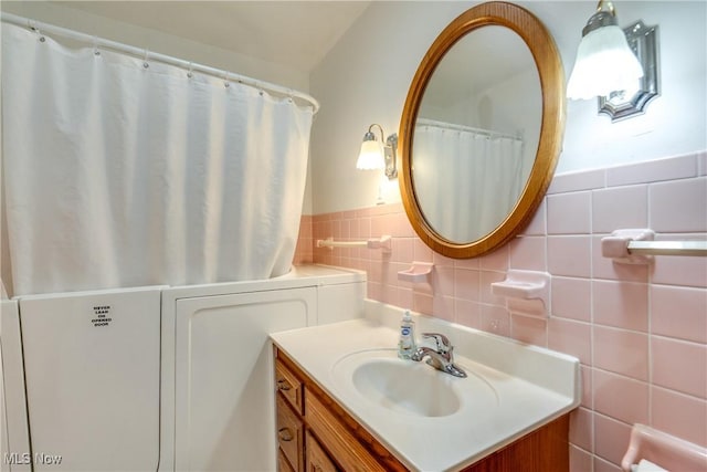 full bathroom with wainscoting, tile walls, and vanity