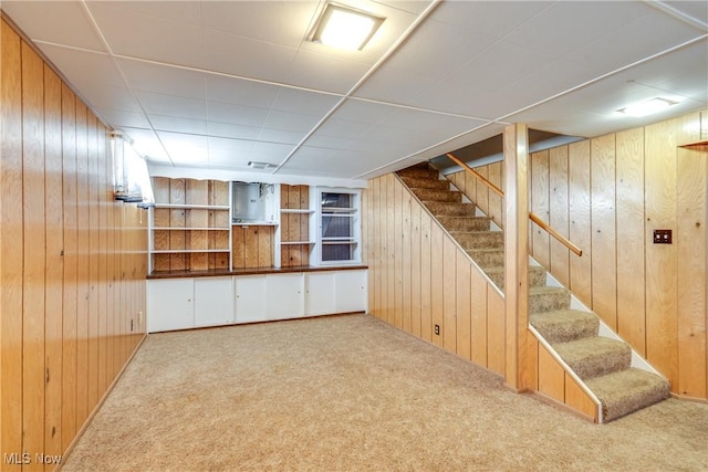 finished basement with carpet flooring, wood walls, and stairway