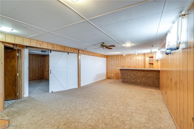 interior space featuring carpet, wood walls, a bar, and a barn door