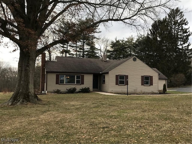 ranch-style home with roof with shingles, a front lawn, and a chimney