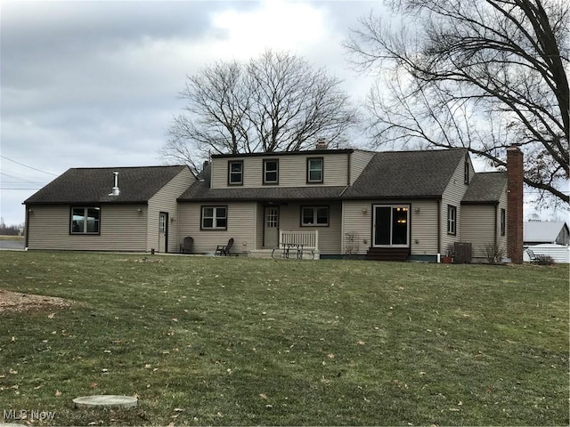 view of front of property with entry steps, a shingled roof, a chimney, and a front lawn