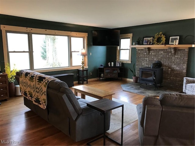 living area with wood finished floors, a wood stove, and baseboards