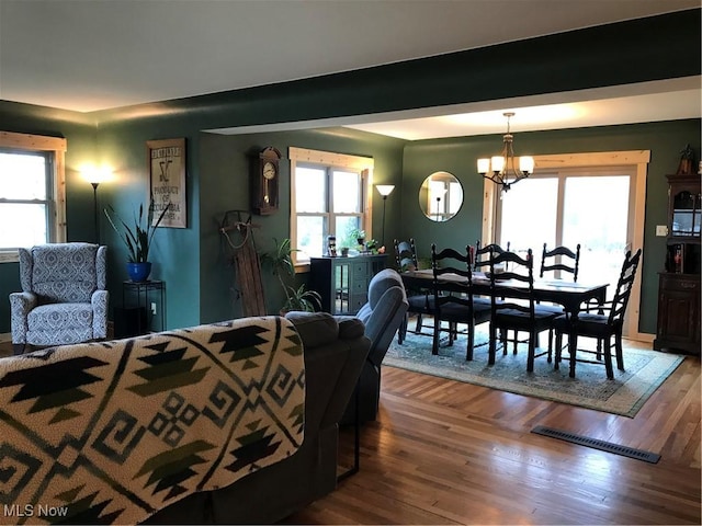 bedroom featuring an inviting chandelier, multiple windows, and wood finished floors