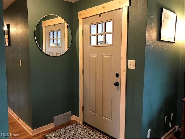 foyer with baseboards, visible vents, and wood finished floors