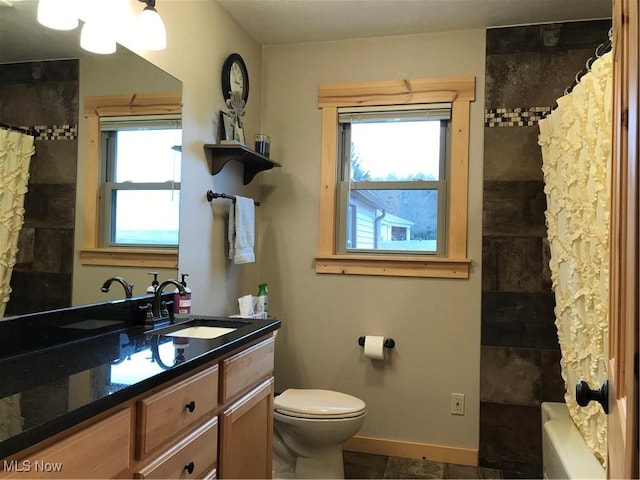 bathroom with toilet, vanity, and baseboards