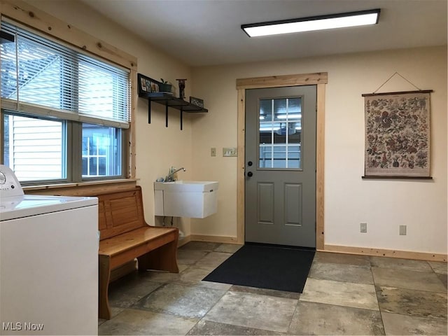 interior space with washer / dryer, laundry area, baseboards, stone finish flooring, and a sink