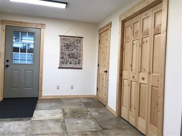 foyer entrance featuring stone finish flooring and baseboards