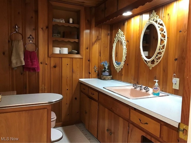 bathroom featuring built in features, vanity, toilet, and wooden walls