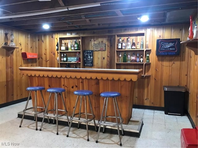 bar featuring a bar, wooden walls, and tile patterned floors