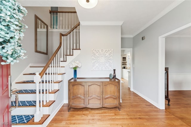 interior space with light wood-style floors, stairway, baseboards, and crown molding