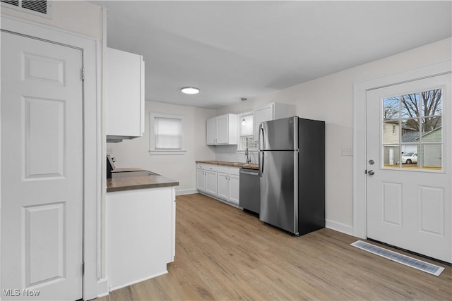 kitchen with visible vents, appliances with stainless steel finishes, white cabinetry, a sink, and light wood-type flooring