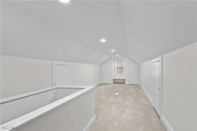 additional living space with recessed lighting, light colored carpet, vaulted ceiling, and baseboards