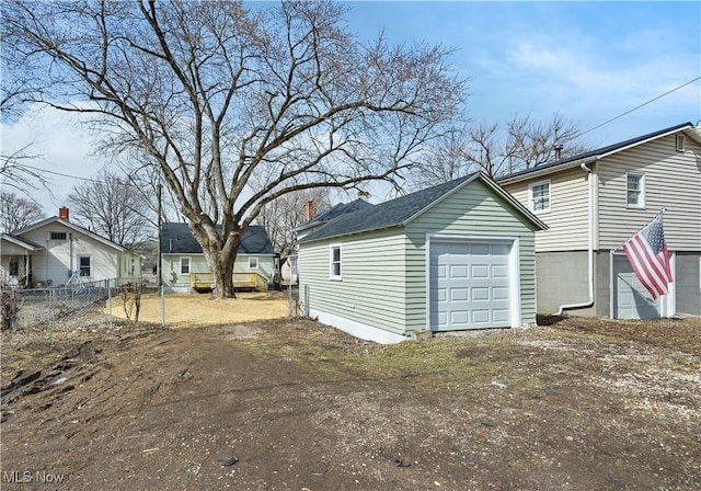 detached garage featuring driveway and fence