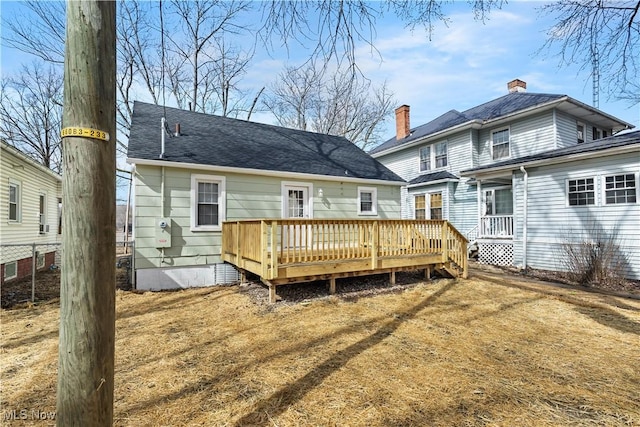 back of house with a shingled roof and a wooden deck