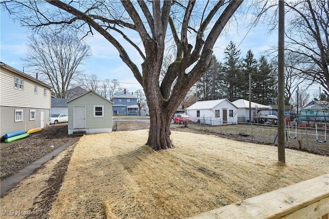 view of yard featuring an outdoor structure, fence, and a residential view