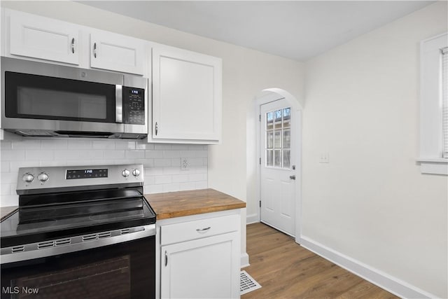 kitchen with tasteful backsplash, white cabinets, wood finished floors, stainless steel appliances, and wooden counters